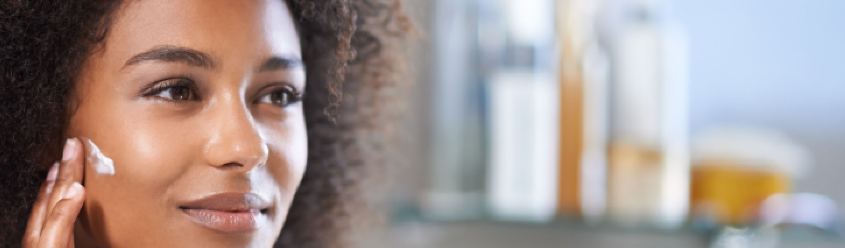 femme métis qui applique de la crème sur son visage