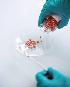 JP_MAIN_MEDICAMENTS Visual of medications being poured into a dish by a hand wearing green gloves.